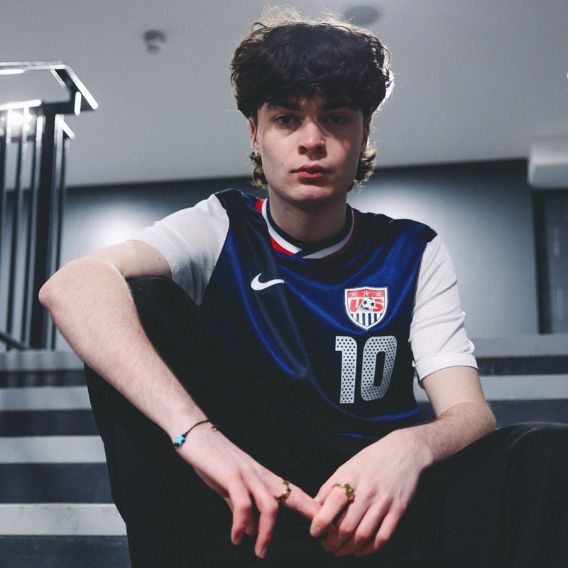 Man sat on stairs wearing superb vintage USA football shirt from 2010s