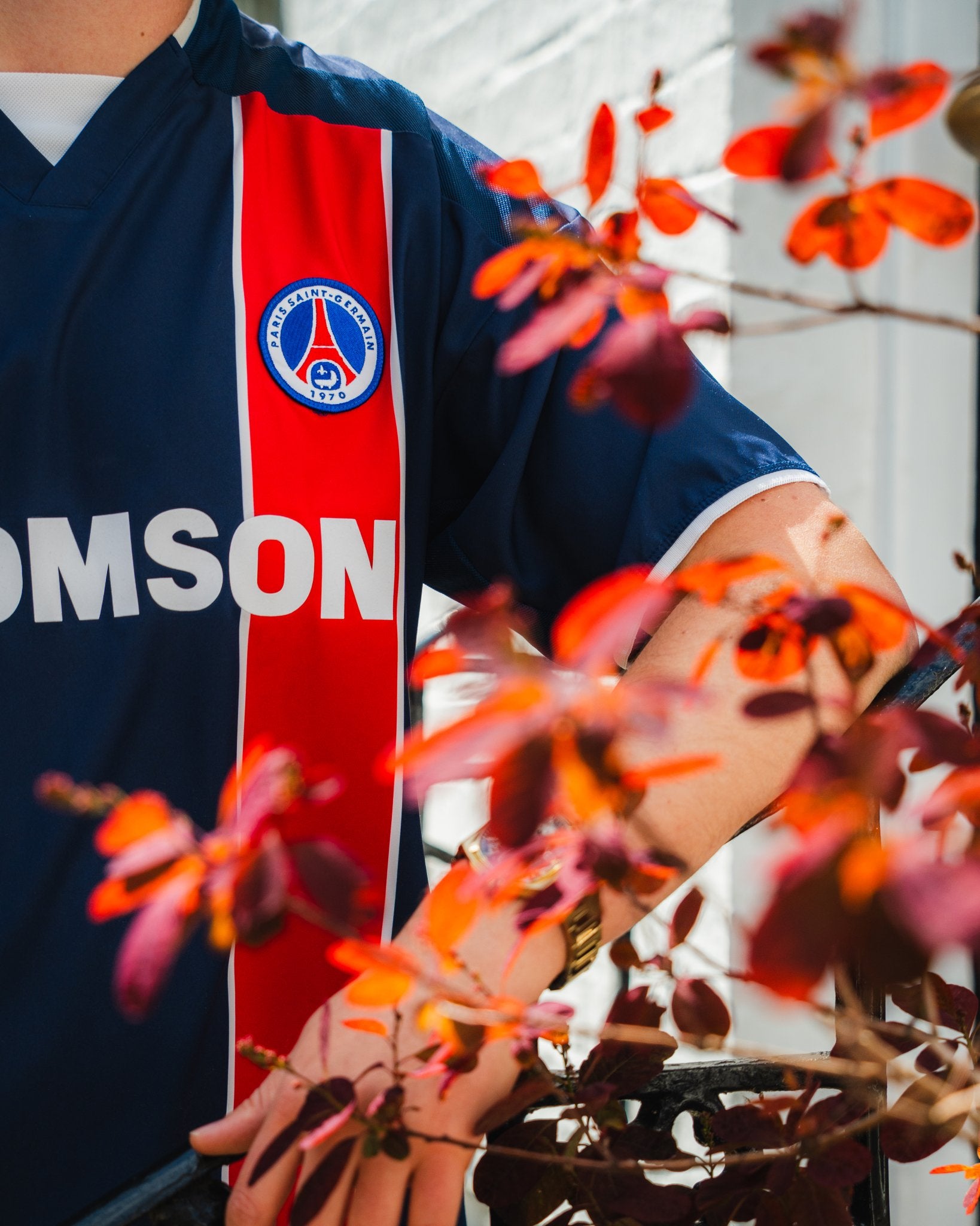 Person wearing a sports jersey with a visible brand logo, surrounded by red leaves.