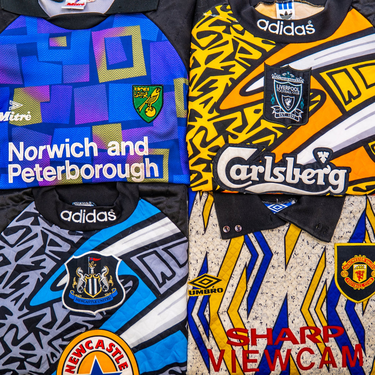 Four football jerseys arranged in a 2x2 grid, each with a different sponsor logo and team crest. The top-left jersey is blue with geometric patterns and Norwich and Peterborough text.
