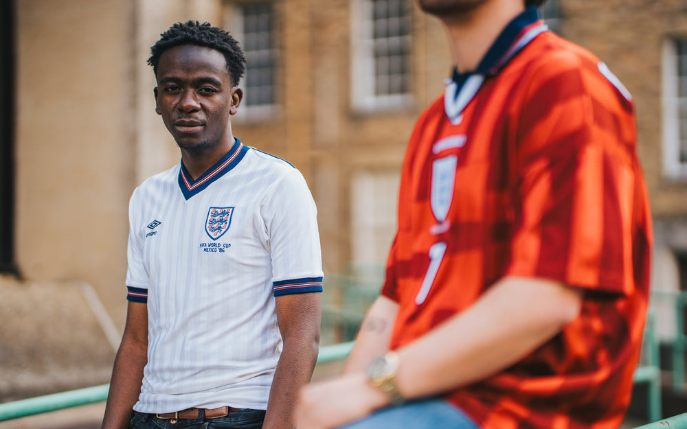 Two individuals wearing England football jerseys outdoors.